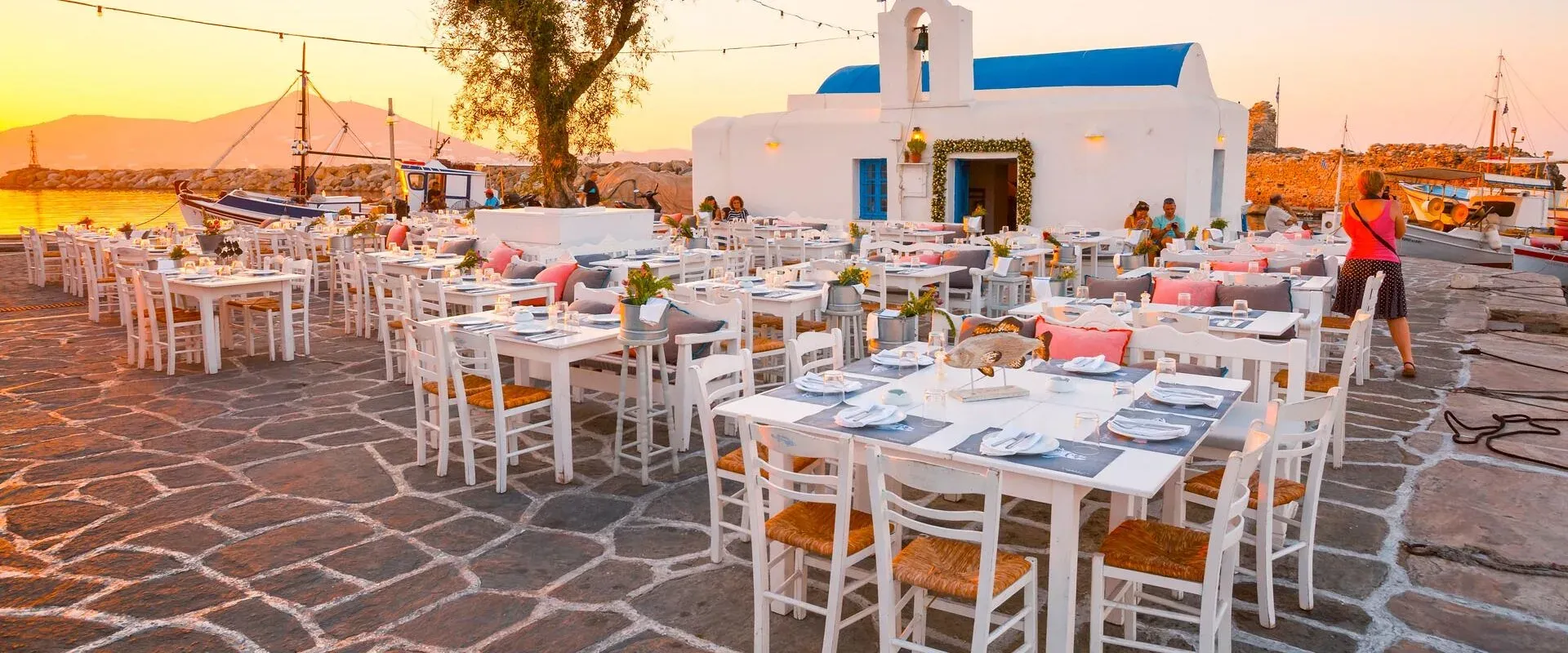 Tables of a harbour taverna at sunset on Paros