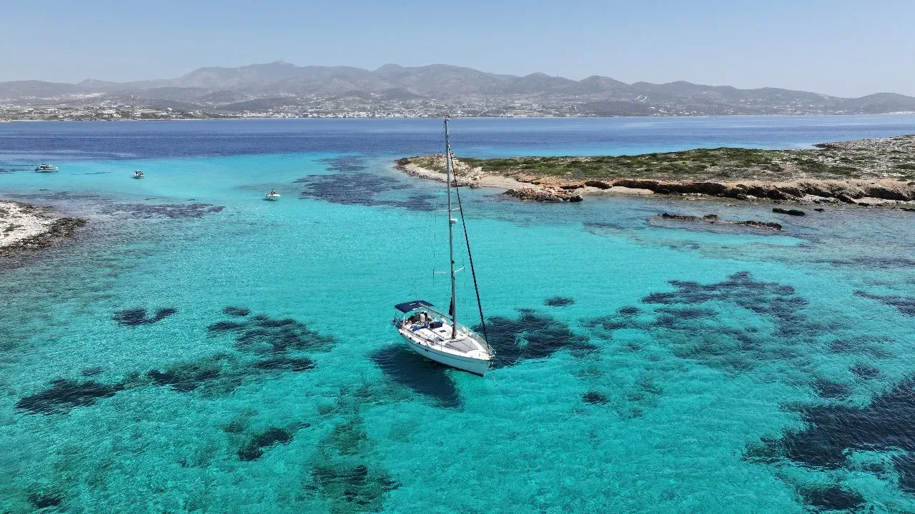 A sailing yacht at anchor in turquoise water off Paros